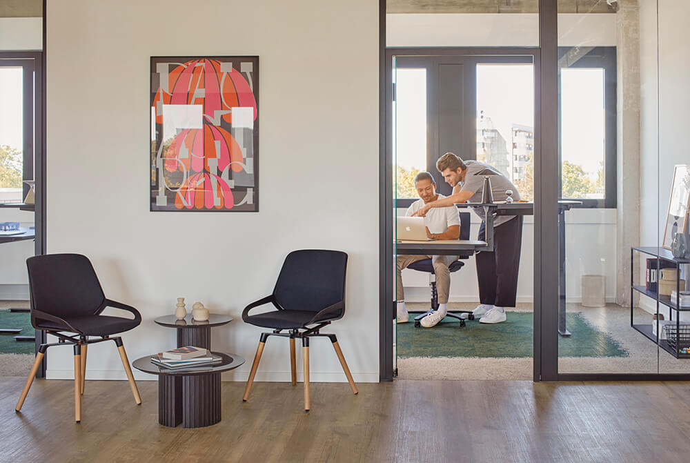 Aeris Numo Comfort mit Holzbeinen in schwarz mit Rückenpolster als Besprechungsstuhl vor Büro